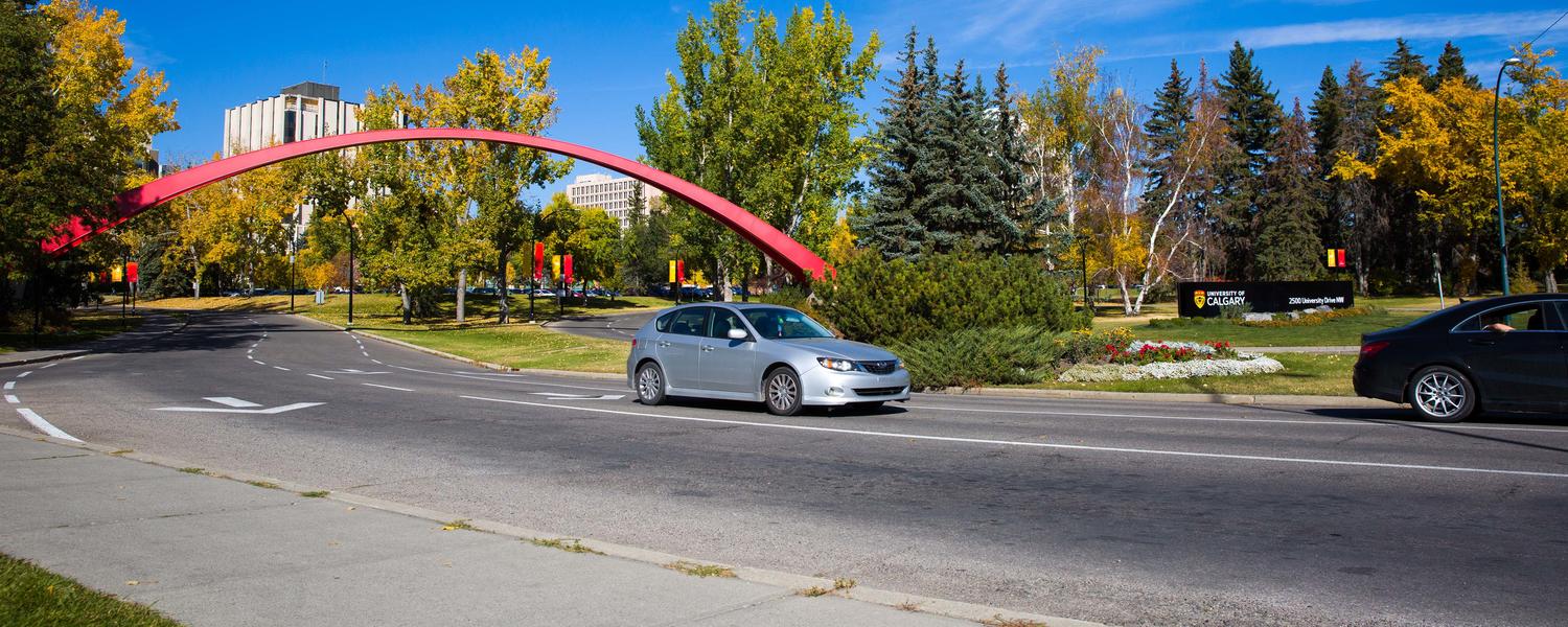 University of Calgary main entrance on a summer day. Red arch with traffic driving out of the university