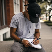 a young guy sitting and writing on a notepad