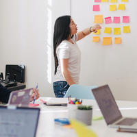 a woman brainstorming with post-it notes with a group in a work room