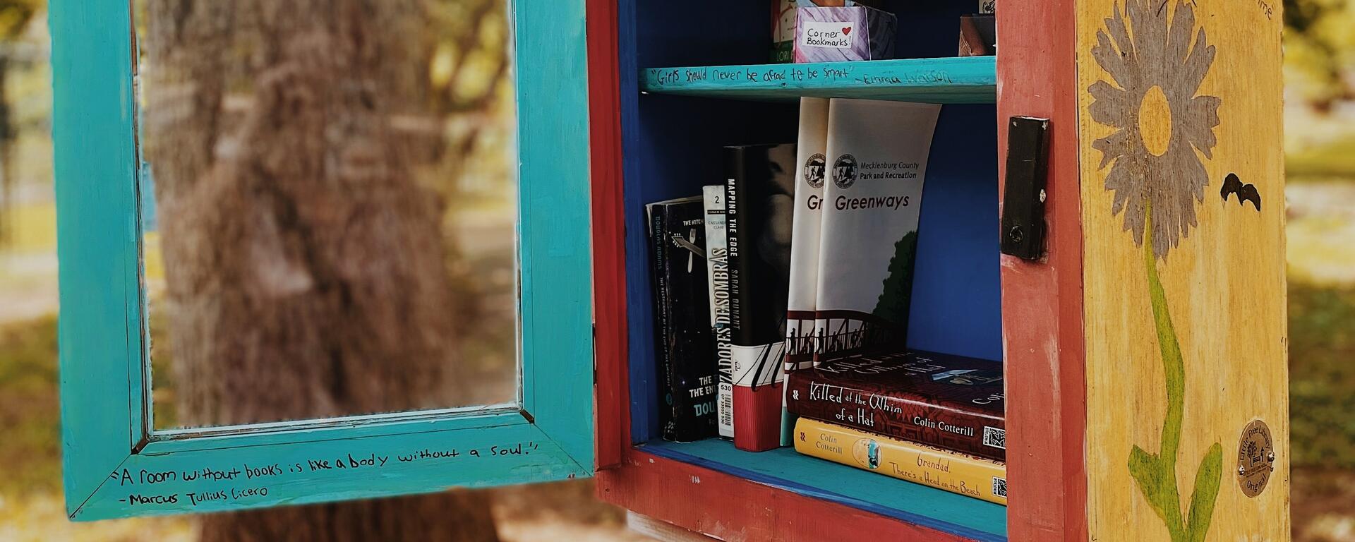 A small wooden bird house filled with free books 