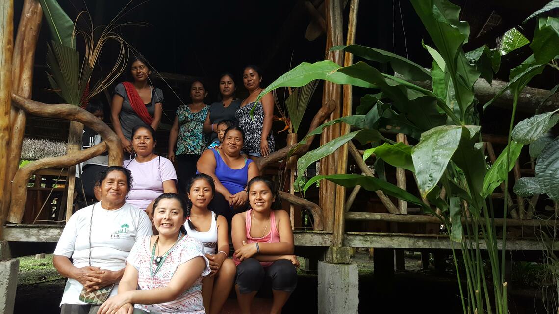 Image of Veronica and other women of different ages sitting outside on steps at a building in Ecuador.
