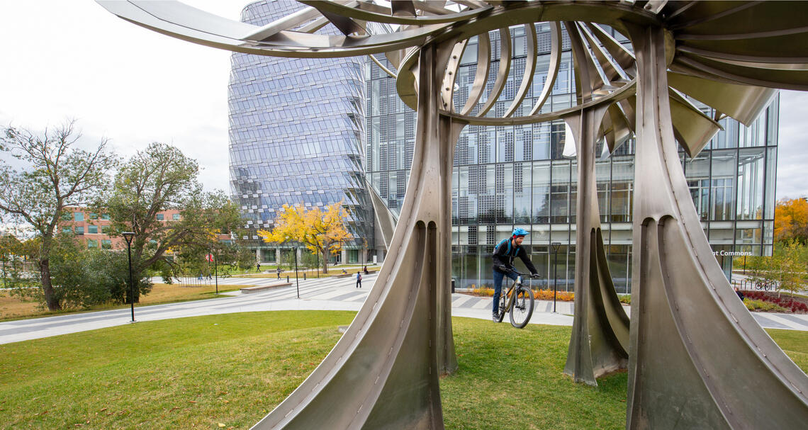 A picture through a scultpture with a cyclist in the background