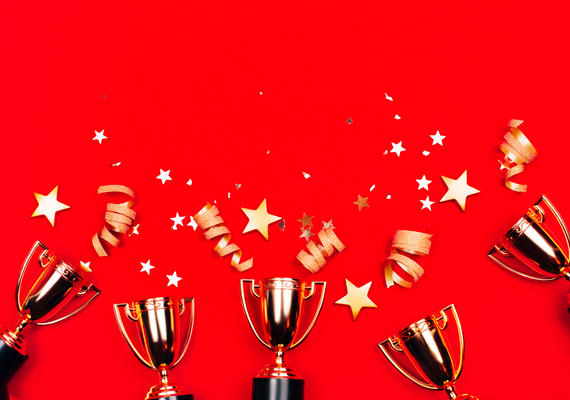Gold trophies with golden confetti on a red background.