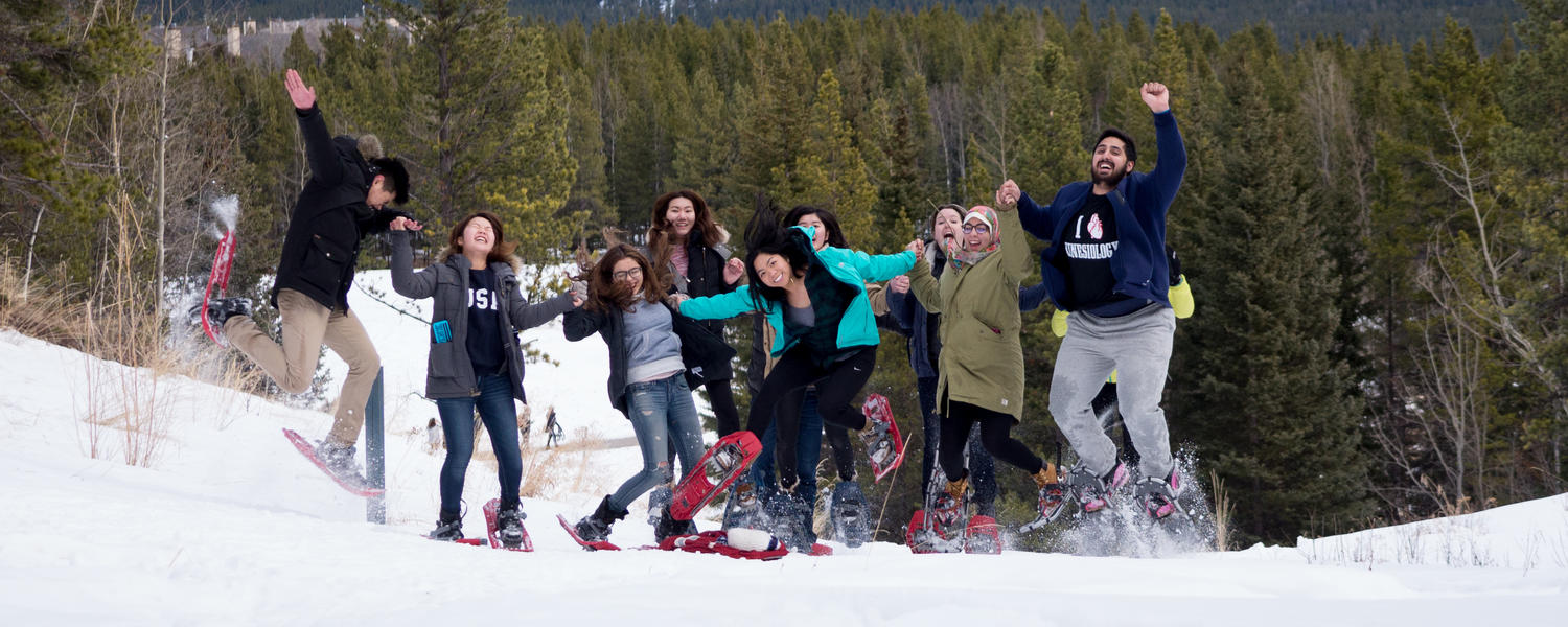 Students with snowshoes jump for joy