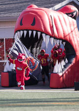 Rex and the Dinos football team running onto the field for KICKOFF 2022