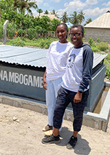 Tinuke Chineme (right) from the University of Calgary and Aliceanna Shoo an intern from Amref Health Africa stand in front of a bin they helped build for biowaste treatment.
