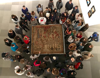 A crowd of individuals learning about an artifact 