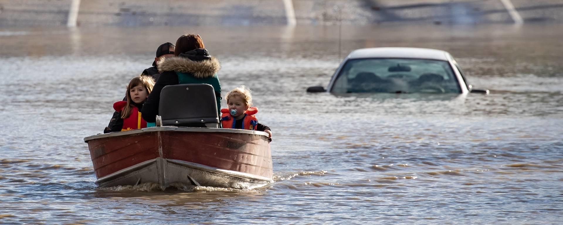 A woman and children who were stranded by high water due to flooding are rescued by a volunteer operating a boat in Abbotsford, B.C., in November 2021.
