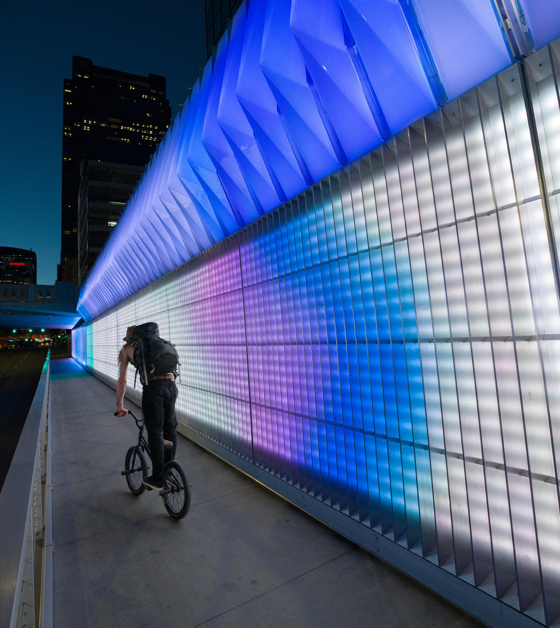 All lit up, a bicyclist moves through the underpass at night.