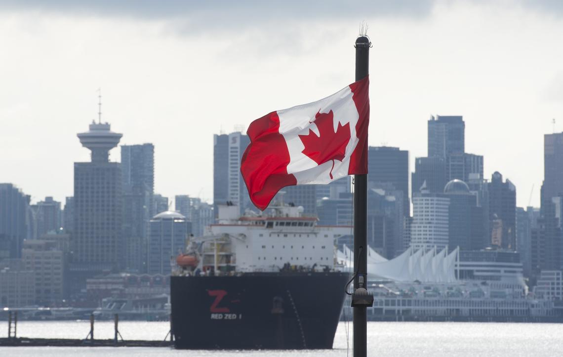  Universities face pressure to ensure their graduate programs have a clear return on investment both for students and for taxpayers. Here, the Vancouver skyline behind a Canadian flag in North Vancouver, B.C., March 24, 2020. 
