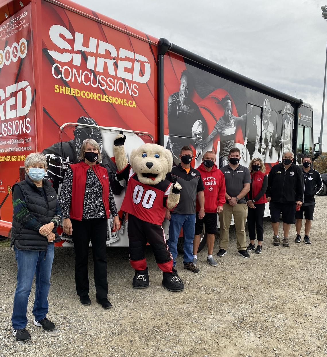 SHRed concussion team members and Bantam hockey league members standing in front of the SHRed Mobile