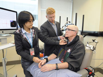 Researchers then place the device on the area of the brain that’s responsible for executive functions — things like multitasking, planning, reasoning and decision-making. Here, research scientist Liu Shi Gan, PhD, and Dr. Lang secure Meier to a frame to stabilize the head and device while it delivers the electric current