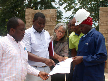 Dr. Dismas Matovelo, far left, discusses plans for the Mbarika health facility construction with Mama na Mtoto staff and Suma JKT Construction