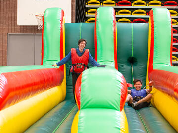 Two people race down a bouncy castle