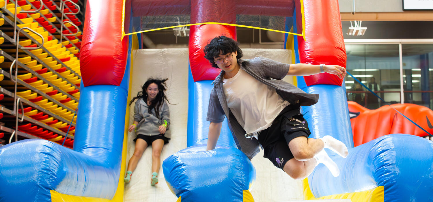 Two people slide down on a bouncy castle