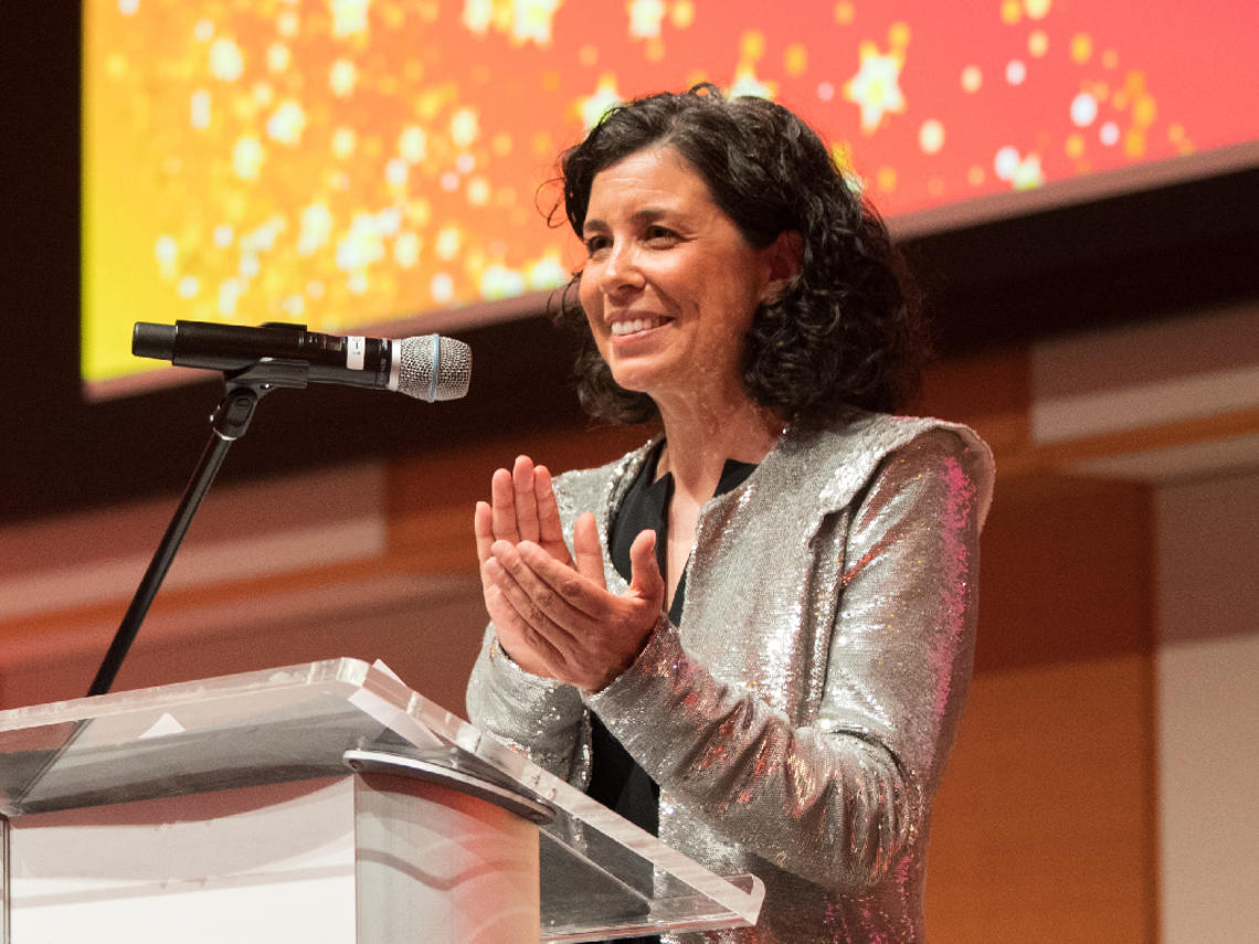 Leslie Reid standing at a podium on stage during the 2022 University of Calgary Teaching Awards Celebration of Teaching.