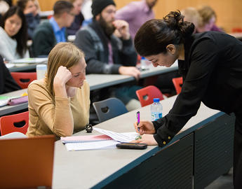 Instructor reviewing a paper with a student in a classroom