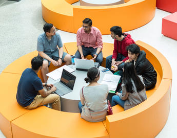 Students sitting together working on laptops and chatting