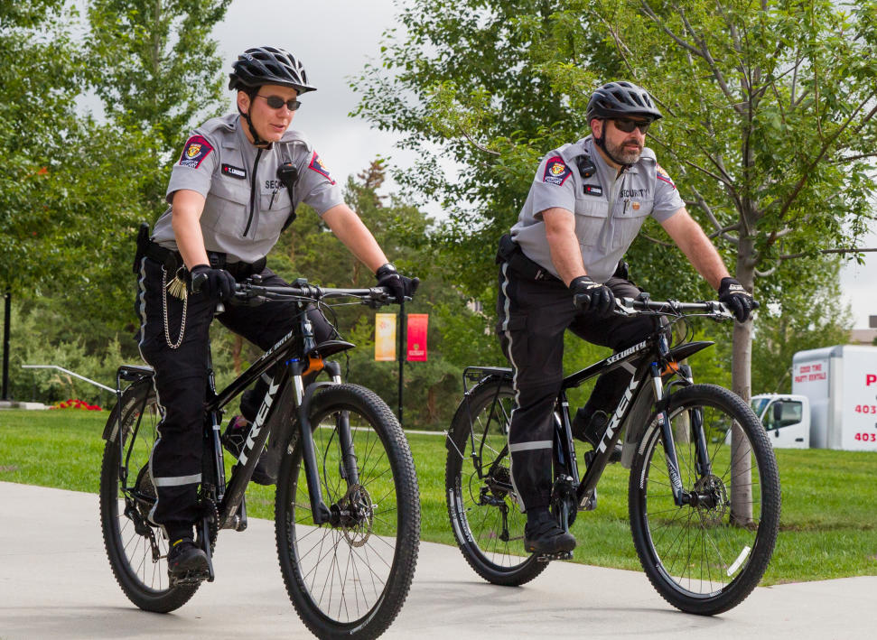 two campus security officers ride their bikes on campus.