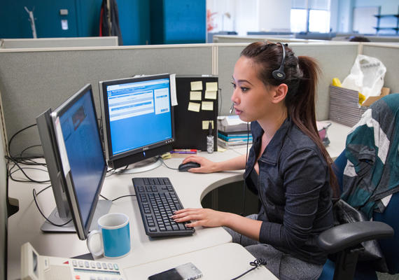 Person sitting at a desk, looking at computer.