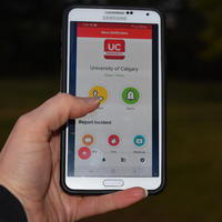 Hand holding phone with UCalgary Alertus Emergency App open