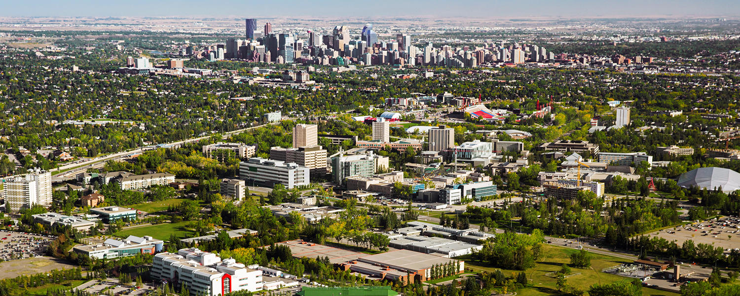 An aerial view of main campus, the research park, and McMahon Stadium in the Calgary landscape, with the downtown skyline in the background.