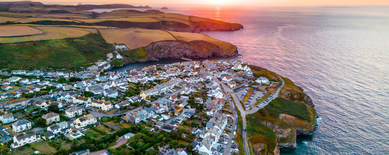 Aerial view of a coastal town, lit by a colourful sunrise