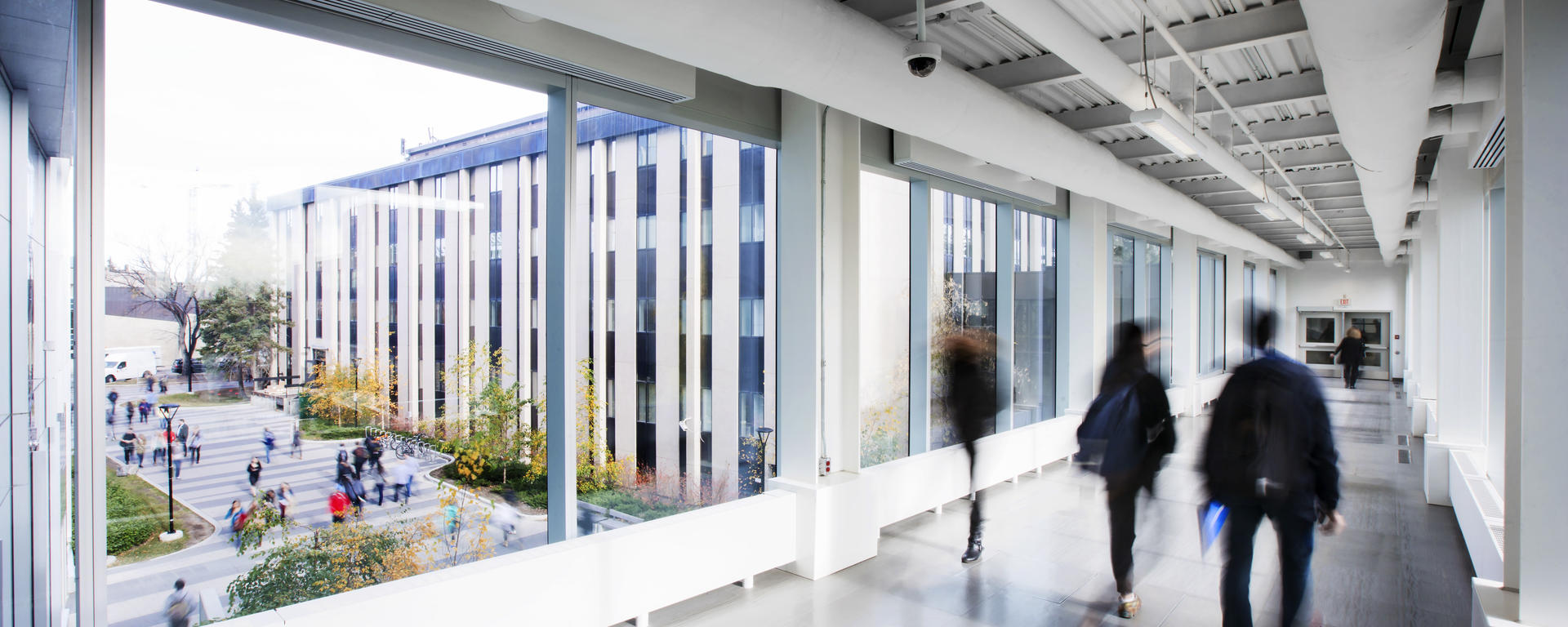 Students walking down a UCalgary +15 with views of the university outside.