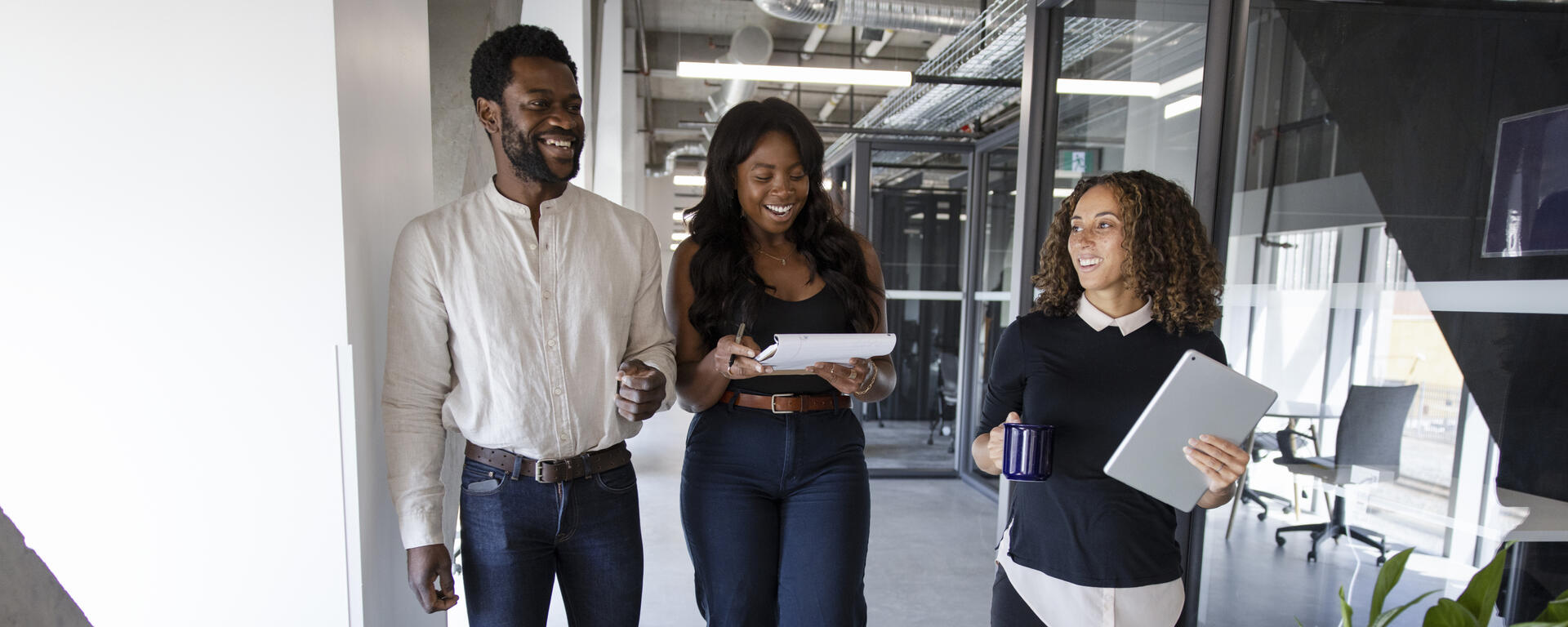 Three people walking together in an office and smiling.