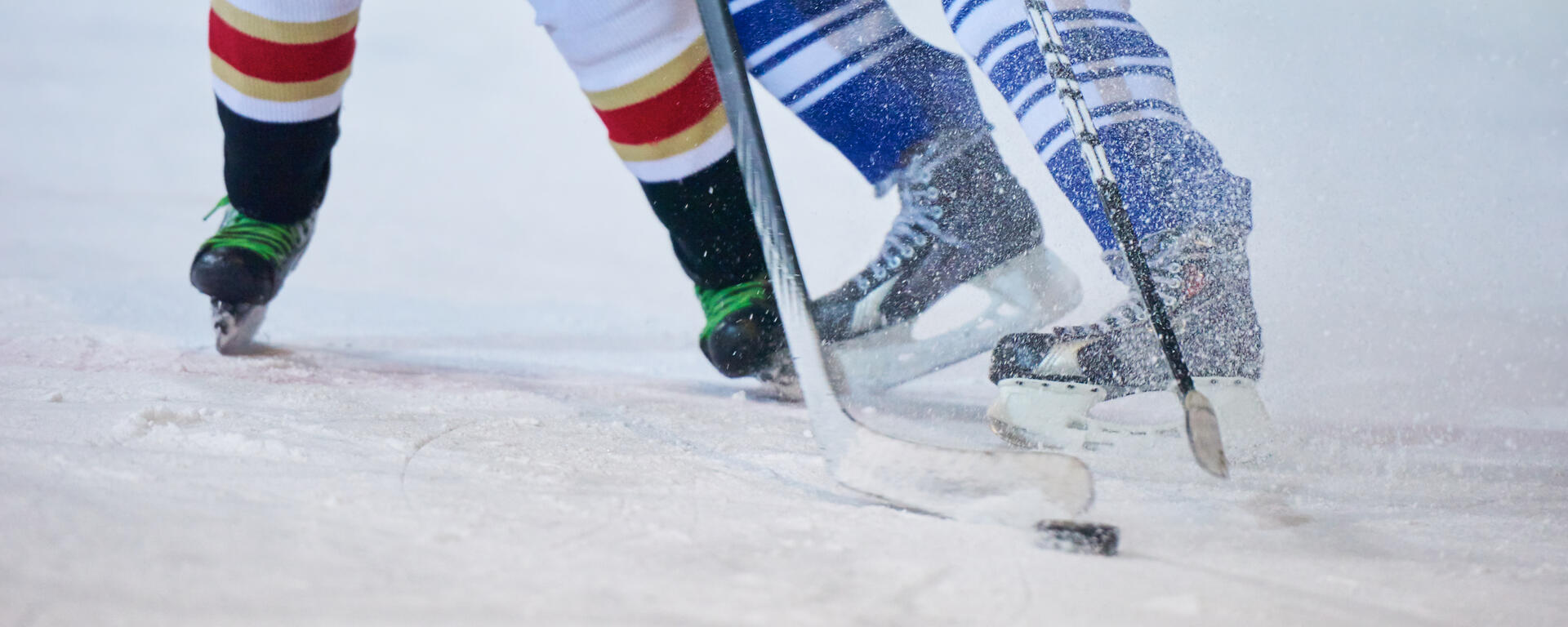 Skates and socks of two hockey players battling for the puck