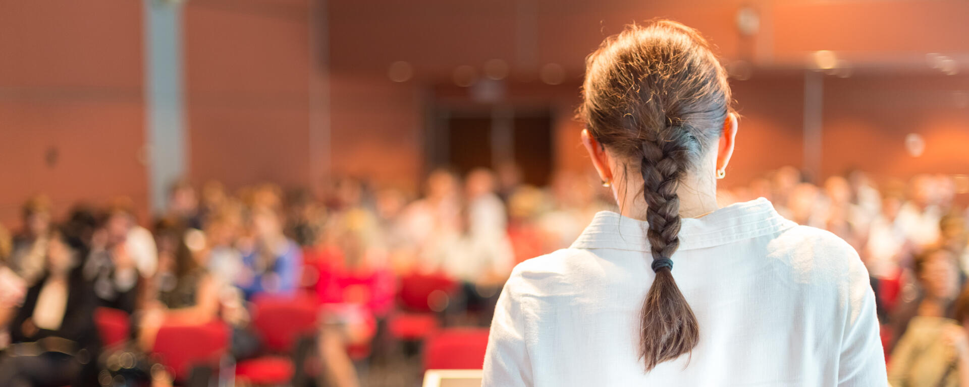 The back of a someone presenting to a full classroom.