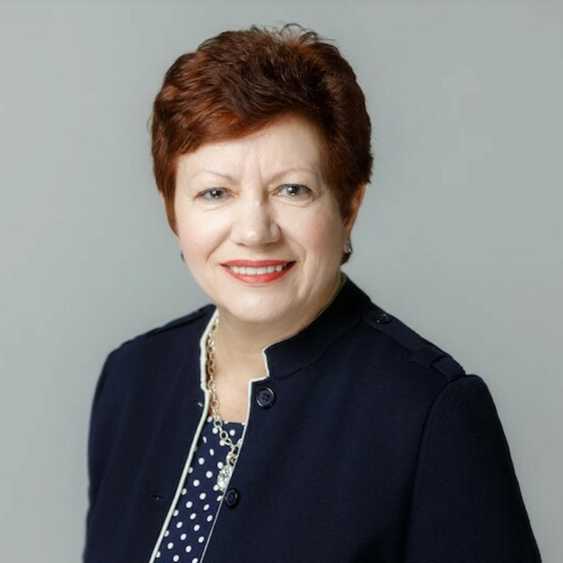 Carmelina Riccio smiling at the camera with a grey background