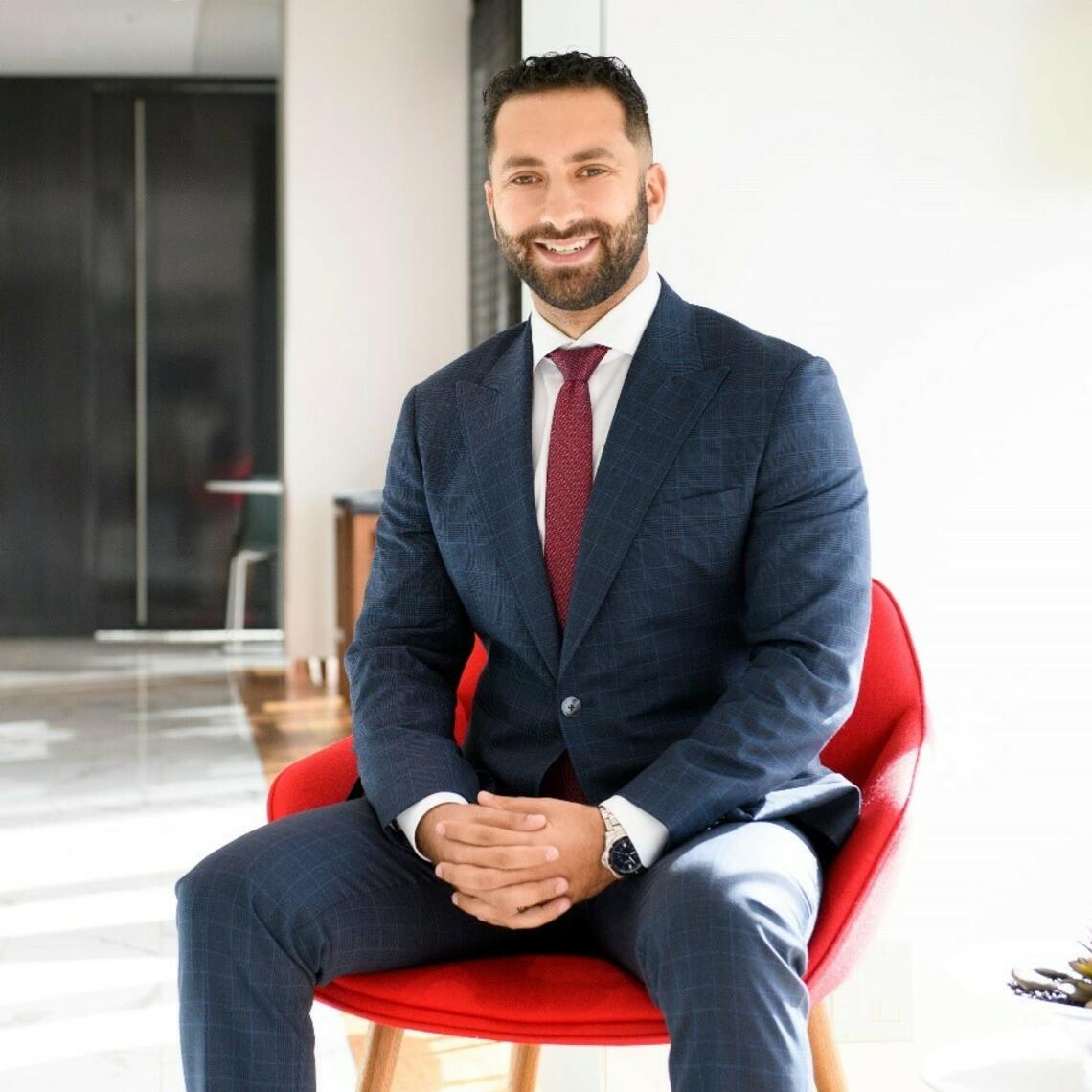 Ali smiling at the camera while sitting on a red chair