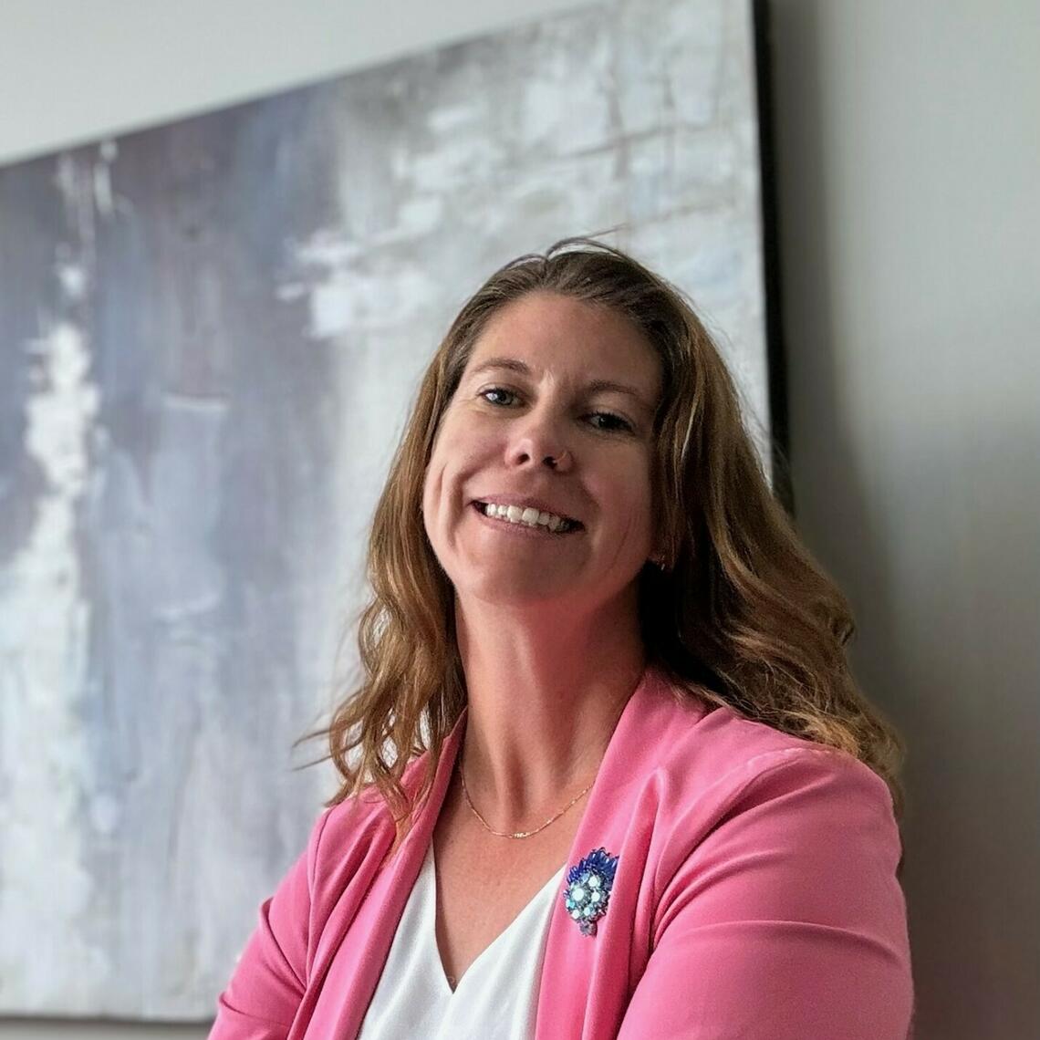 Keely Willment smiling at the camera with a painting in the background