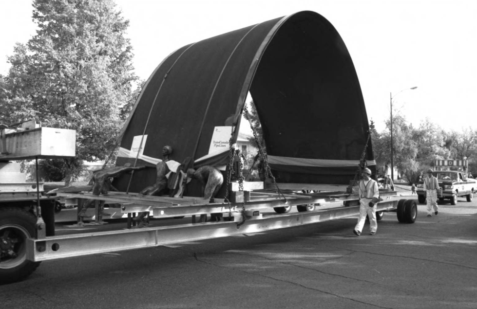 Image of a truck hauling the Olympic Arch, designed by Toronto architect Jack Diamond, to the University of Calgary after it had been on display at city hall following the 1988 Calgary Winter Olympics.