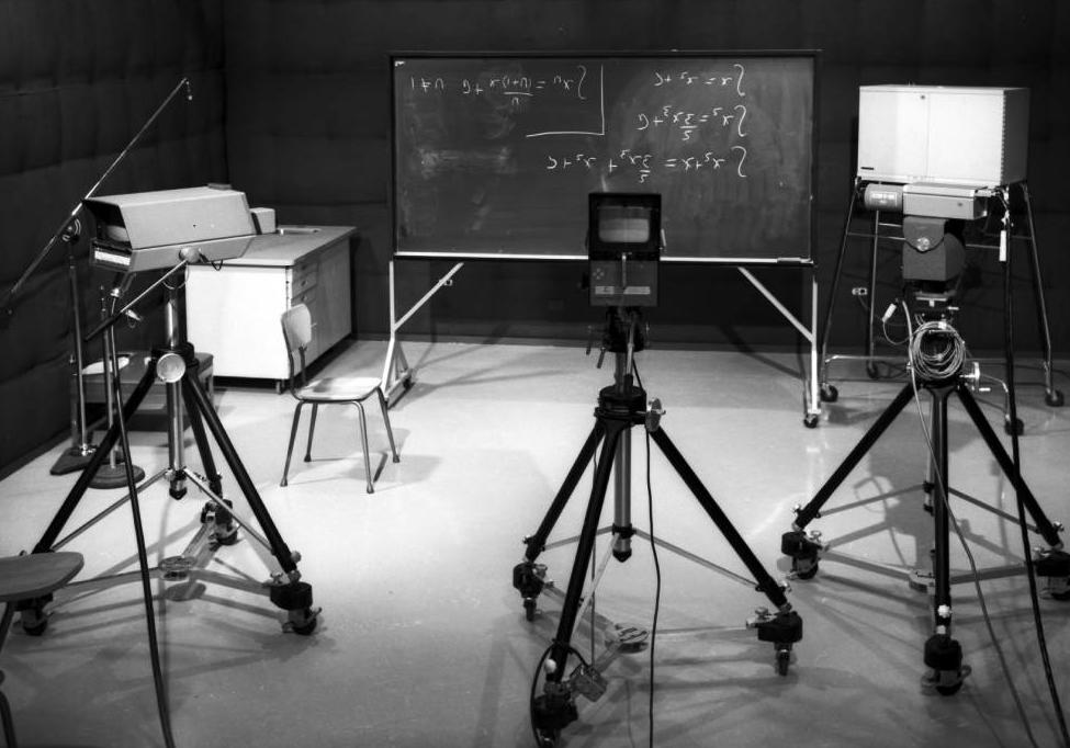 A University of Calgary TV studio with video cameras and a blackboard with four equations written on it.