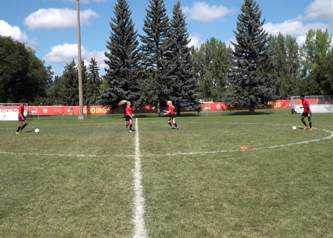 Soccer players performing pass on the ground with turn to open