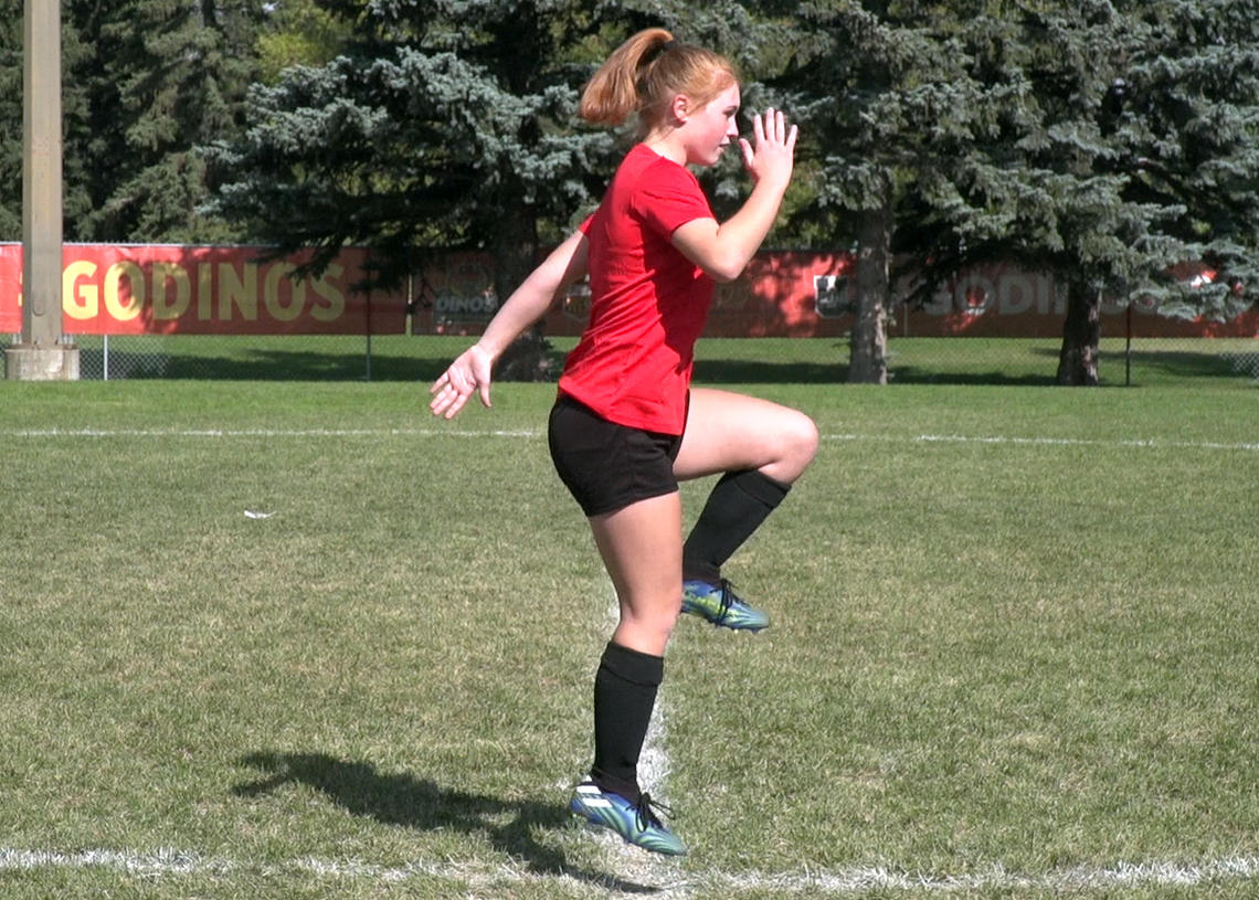 Soccer player performing airplane balance with knee drive and hop