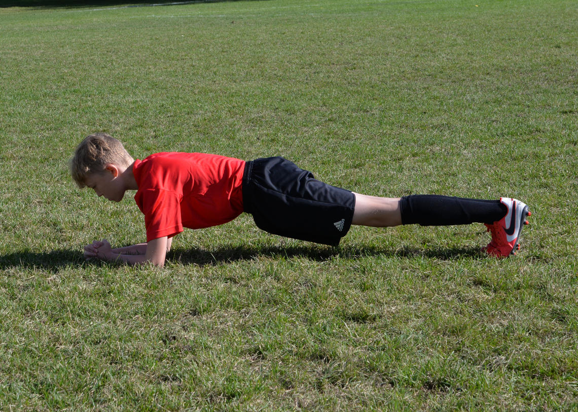 Soccer athlete performing a front plank on elbows