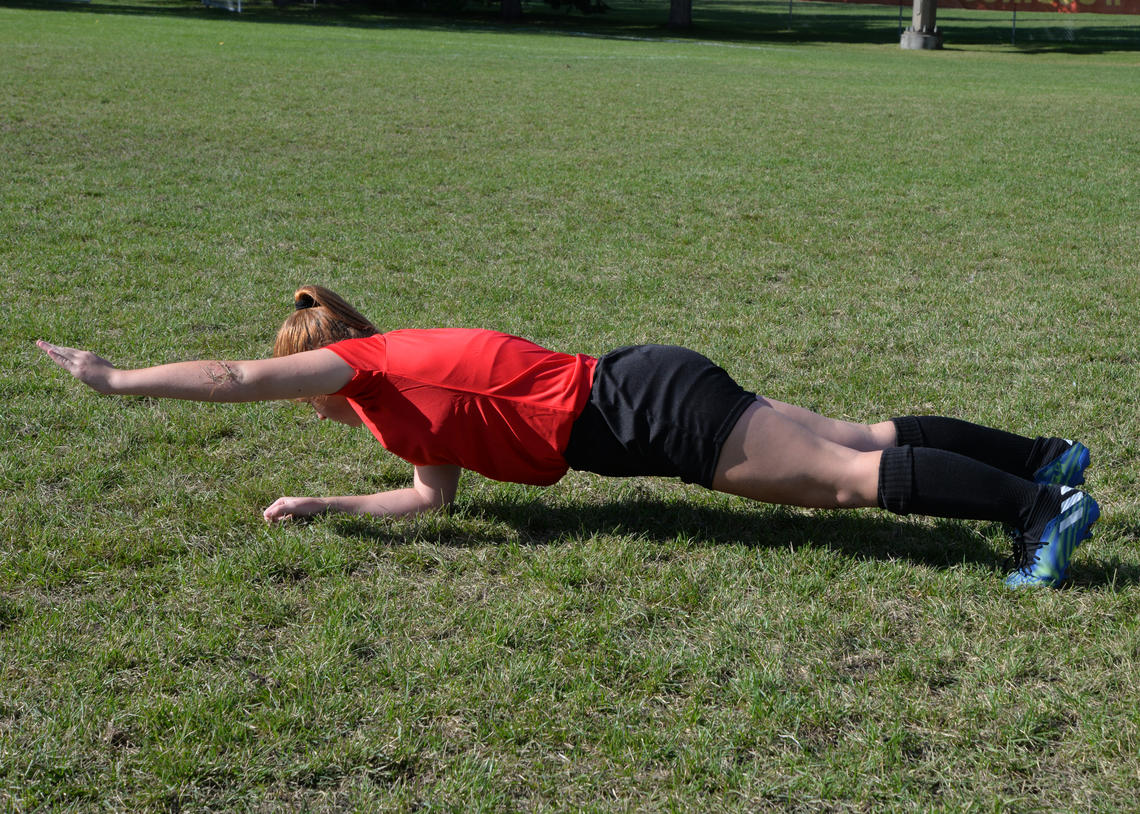Soccer player performing front plank with arm lifts