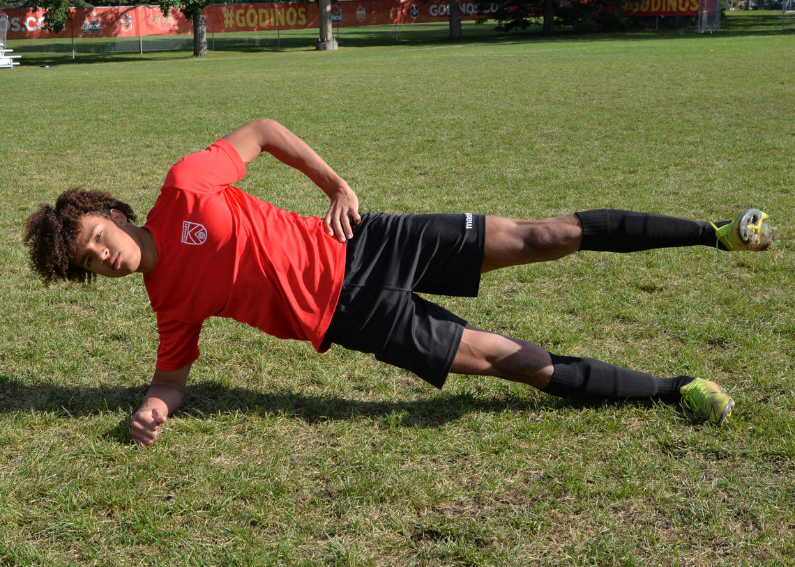 Soccer athlete performing side plank with leg lifts