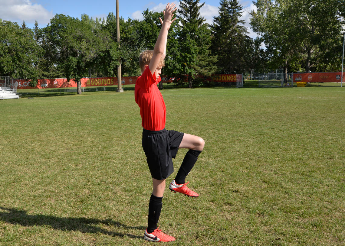 Soccer athlete performing a leg lift during a walking lunge