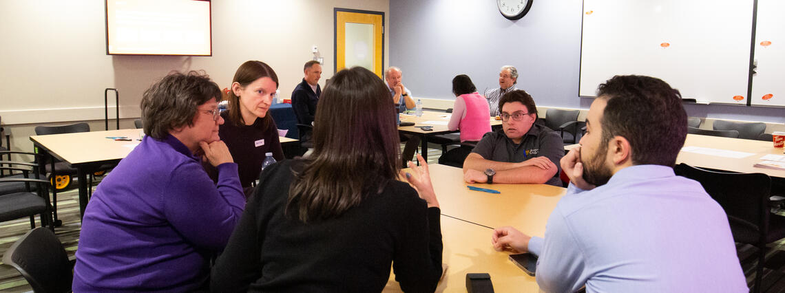 People gathered in a room, sitting at tables, engaging in discussion about the strategic plan.