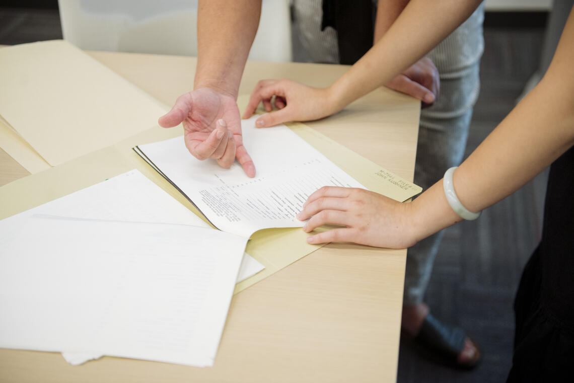 Hands pointing to words on a page.