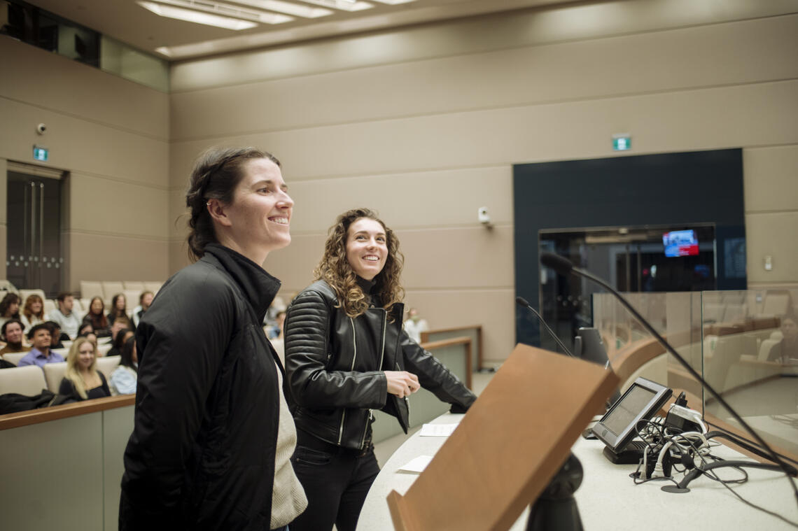 Students Mhairi McGuigan and Annica Best present in front of classmates to a panel of experts inside council chambers at city hall.