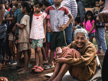 Image of smiling elderly woman sitting on ground