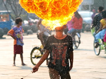 Image of a young boy blowing fire in the street