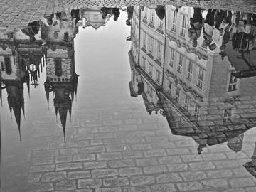 Image of European architecture reflected in a puddle on cobblestone street
