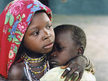 Image of a girl holding an infant wrapped in colourful scarf