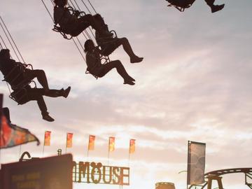 Image of silhouettes riding a carnival swing at sunset